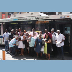 Members of the BOAC team pose with their plaques in front of a City bus near Times Square.