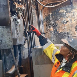 Safety Director Celeste Kirkland points to burned power panel with melted meter at the site of Dec 11 explosion
